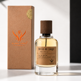 A bottle of  'Belle de Tanger' perfume with a dark brown cap, next to its brown kraft paper box with an orange logo, set against a split white and black background with soft leaf shadows.