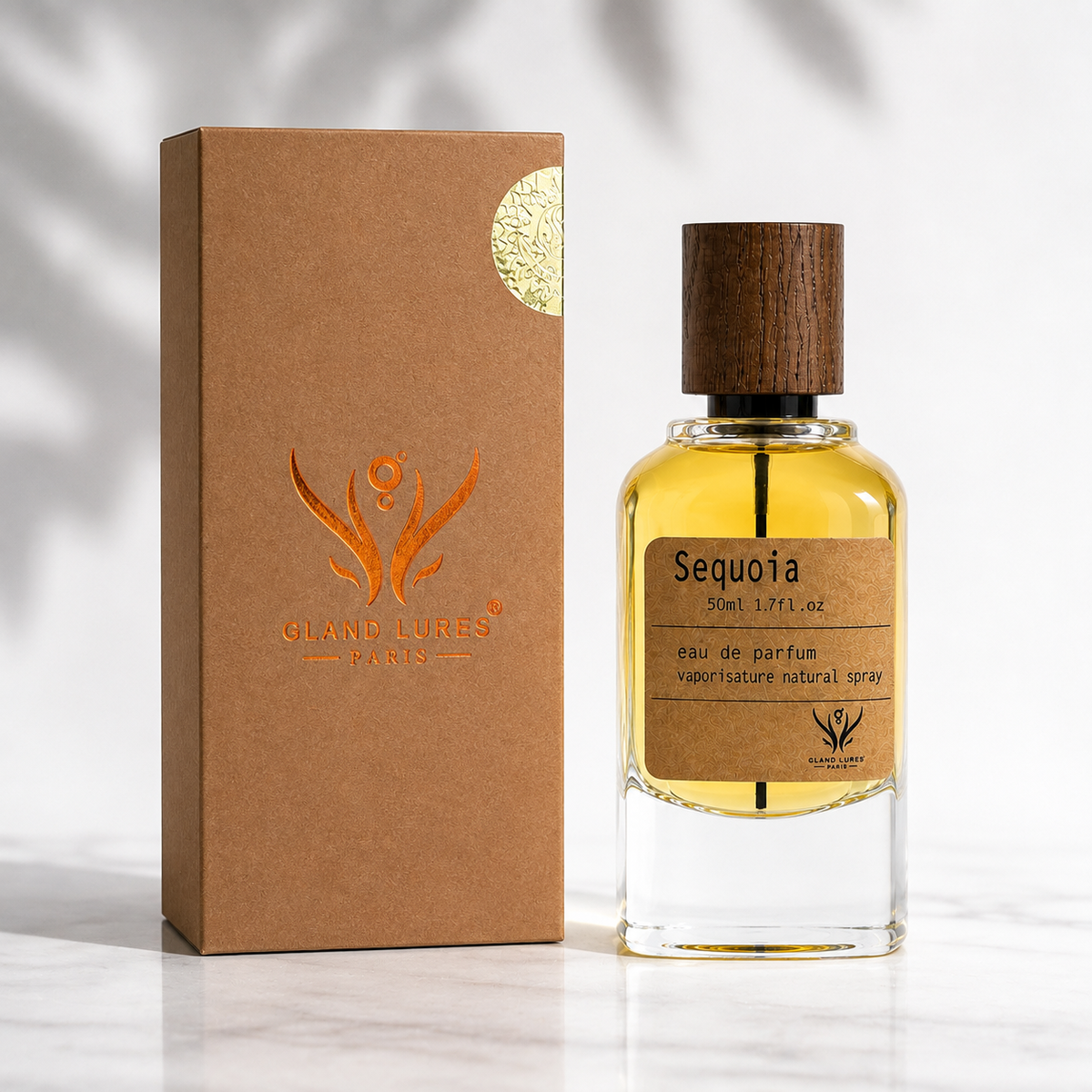 A bottle of Grand Lures Paris Sequoia Eau de Parfum with a dark wood cap, next to its brown kraft paper packaging box with an orange logo and gold seal, set on a white marble surface with soft leaf shadows.