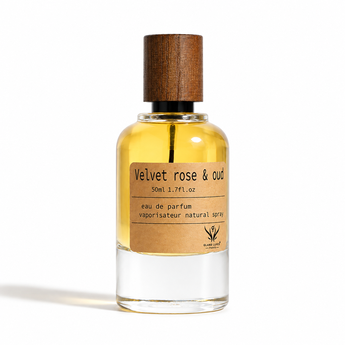 A 50ml clear glass perfume bottle with a brown wooden cap and a brown kraft paper label reading 'Velvet rose & oud' by the brand 'sacred earth', set against a plain white background.